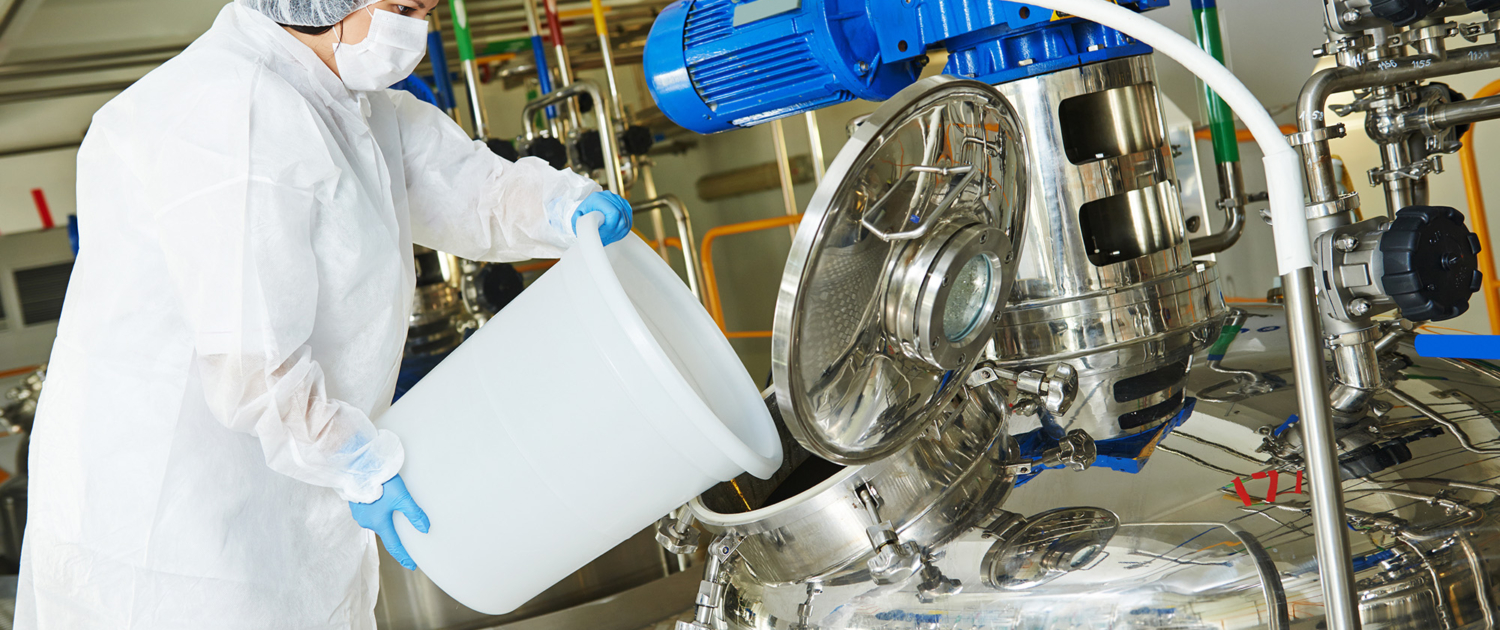 Worker blending ingredients in large mixer