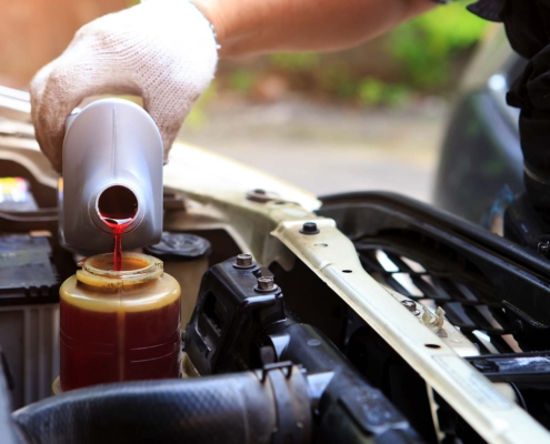 Worker topping off automotive fluids in car