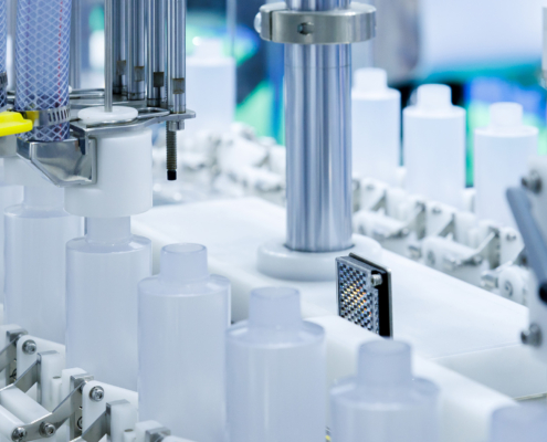 robot arm moving plastic bottle to conveyor belt of auto capping and labeling machine